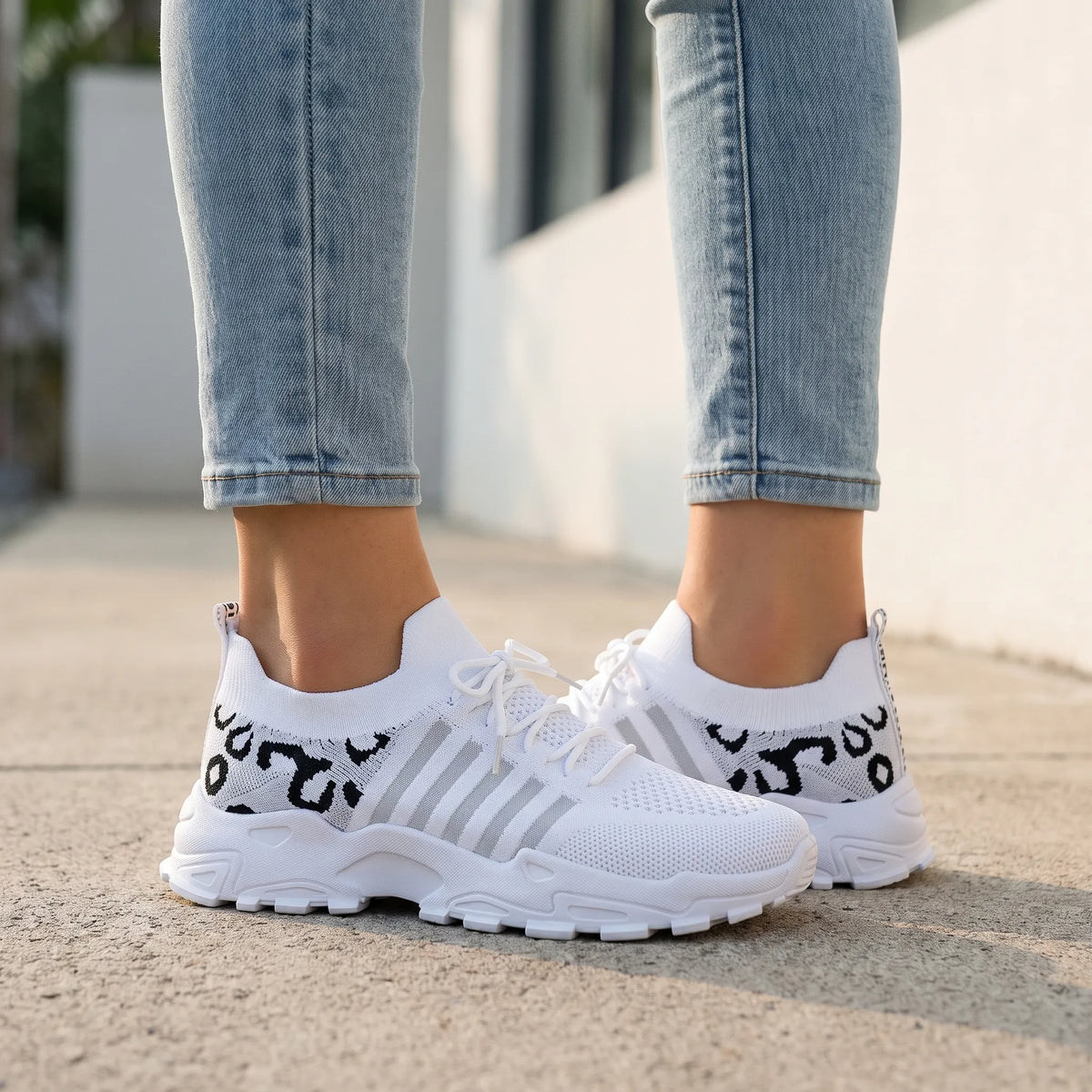 Hvide sneakers med snørebånd, kraftig sål og sort grafisk hælmønster